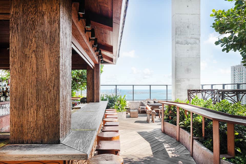 Elevated wooden terrace with ocean view, featuring rustic wood columns and modern railing overlooking coastal landscape