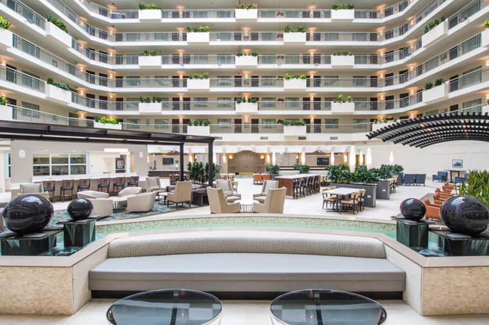 Modern circular hotel atrium lobby with curved balconies, seating areas, and decorative plants