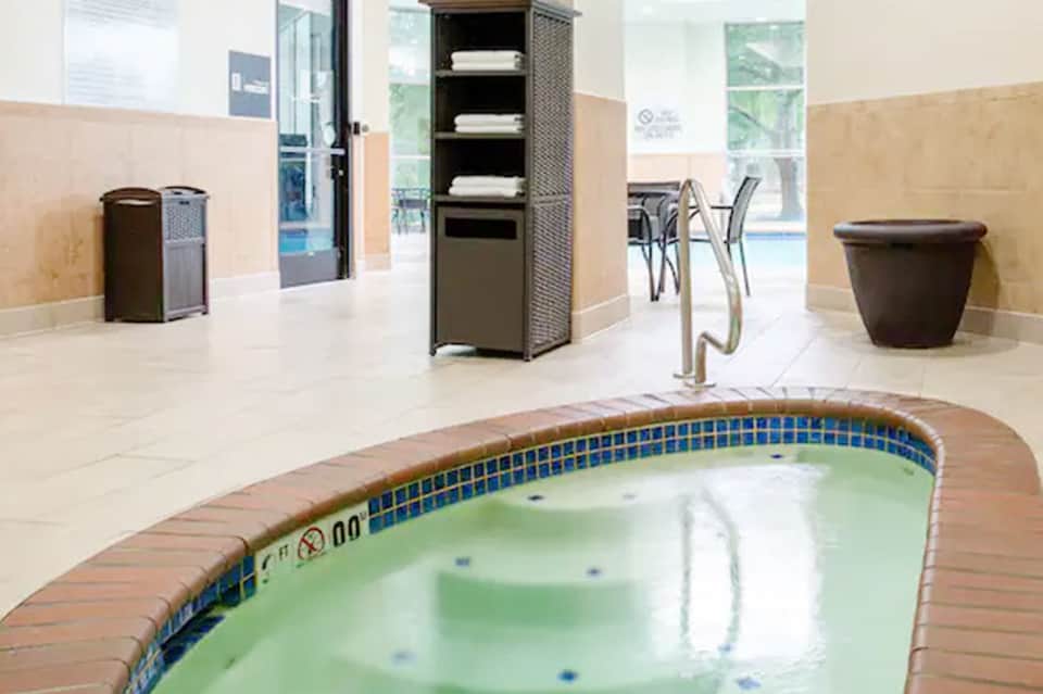 Indoor spa area with hot tub and tile flooring near pool entrance