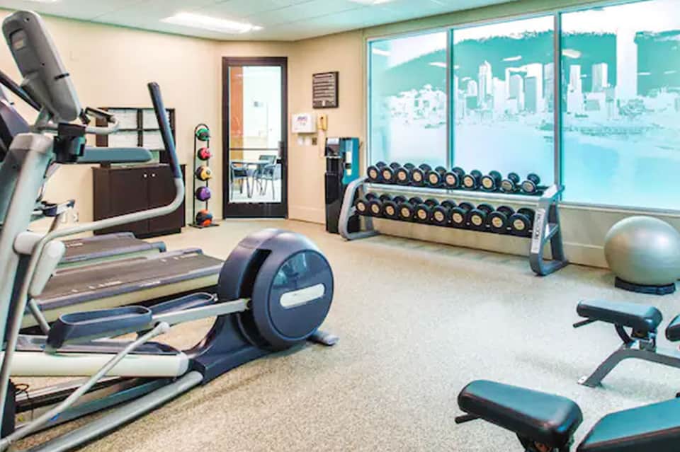 Fitness center with treadmills, dumbbells, exercise equipment, and water views through large windows
