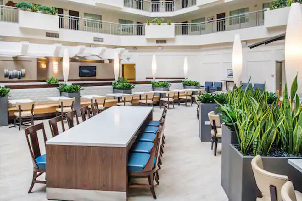 Circular multi-level atrium lobby with white columns, plants, and seating areas