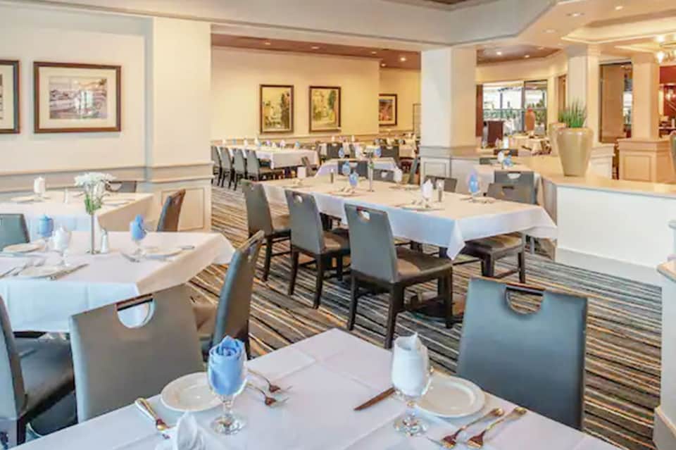 Elegant formal dining room with white tablecloths, gray chairs, and warm lighting
