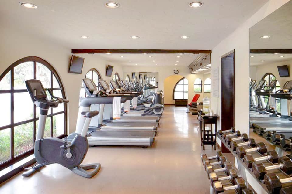 Spacious fitness center with rows of treadmills, exercise bikes, and dumbbells