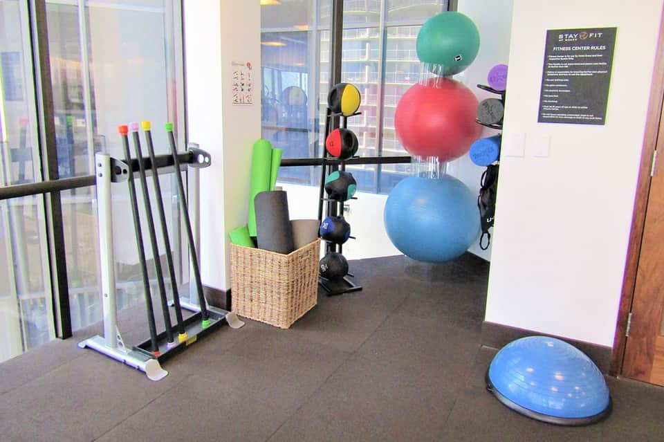 Fitness center with exercise equipment including colorful stability balls, resistance bands, and dumbbells