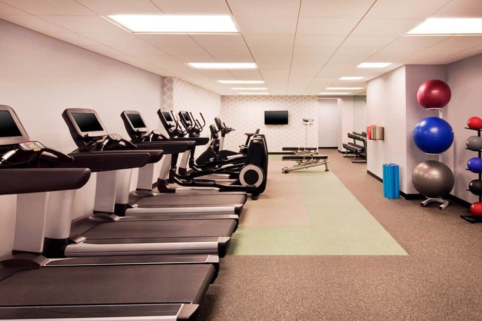 Modern fitness center with treadmills, exercise bikes, cardio equipment, and colorful stability balls