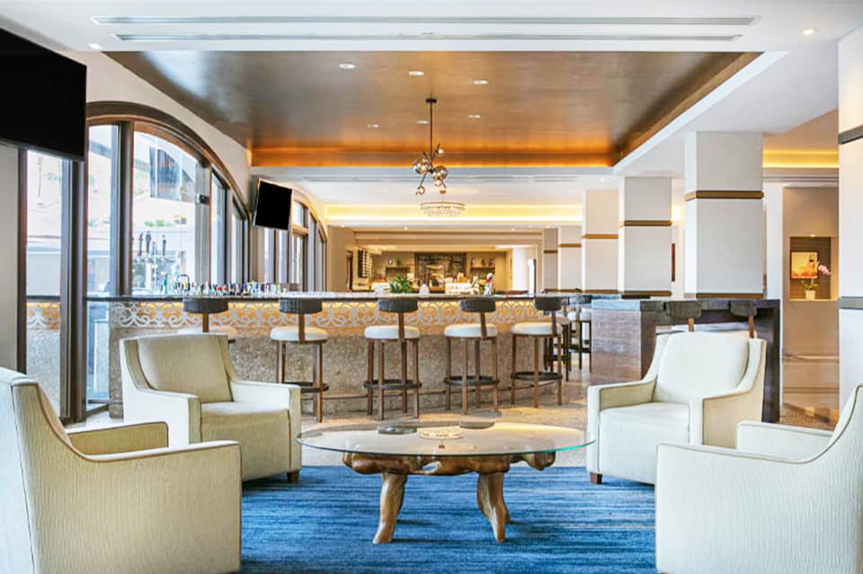Upscale hotel bar and lounge with bar seating, elegant furnishings, and amber lighting