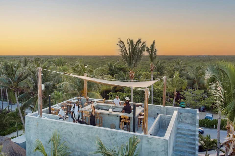 Rooftop bar and lounge with ocean and palm tree views at golden hour