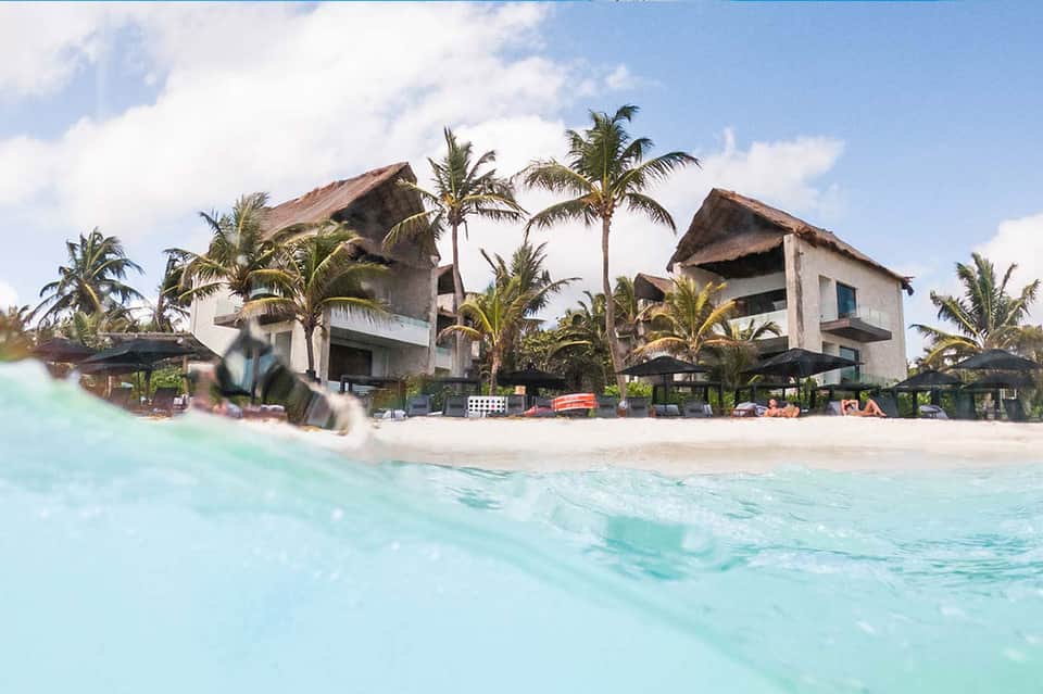 Beachfront resort with thatched-roof structures and turquoise ocean water