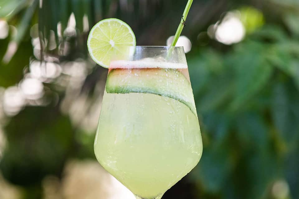Refreshing lime cocktail with straw garnished on outdoor table