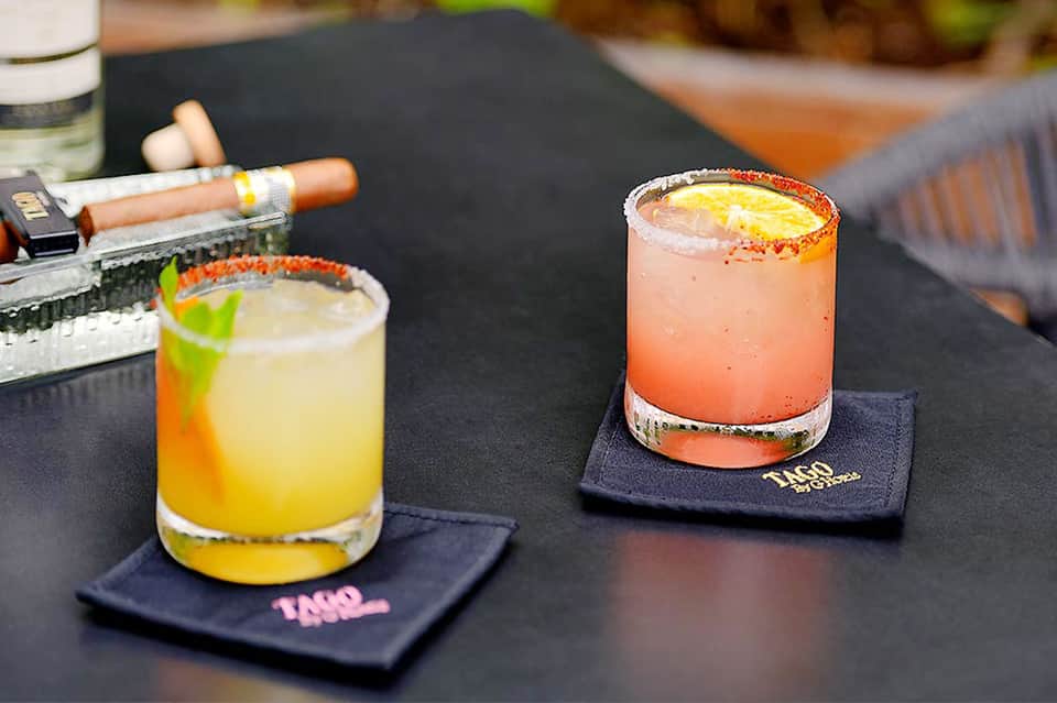 Colorful cocktails on bar counter with chili-lime rimmed glasses and decorative coasters