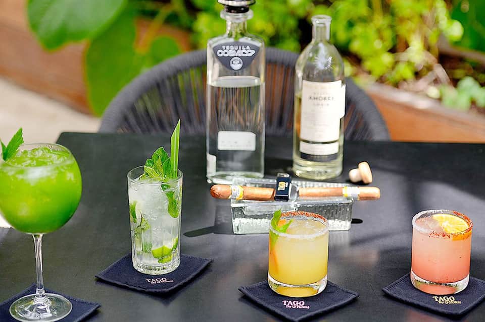 Colorful cocktails with tequila and spirit bottles displayed on outdoor bar setting