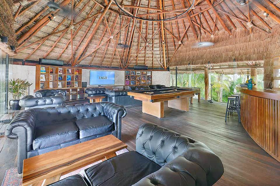 Tiki-style lounge with thatched ceiling, leather seating, pool table, and ocean views