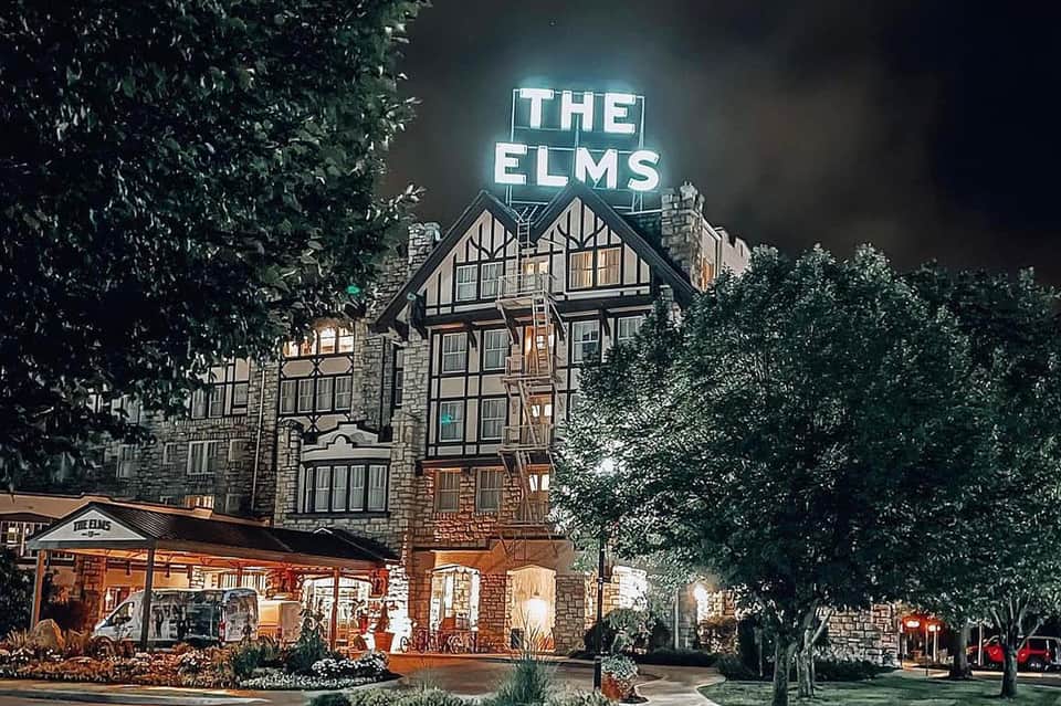 Historic Tudor-style building 'The Elms' lit at night with ivy-covered stone exterior