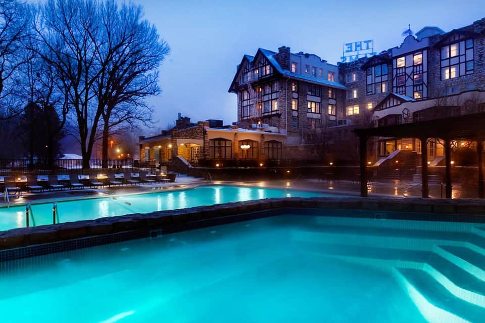 Illuminated geothermal spa pools with hot springs at dusk next to historic building
