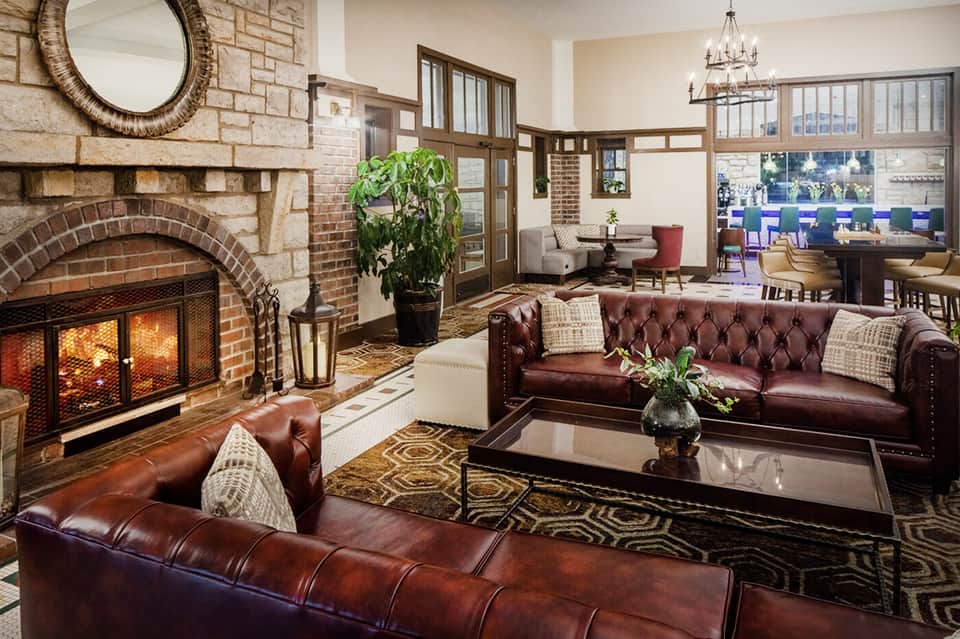 Elegant hotel lobby with fireplace, leather seating, chandelier, and upscale furnishings