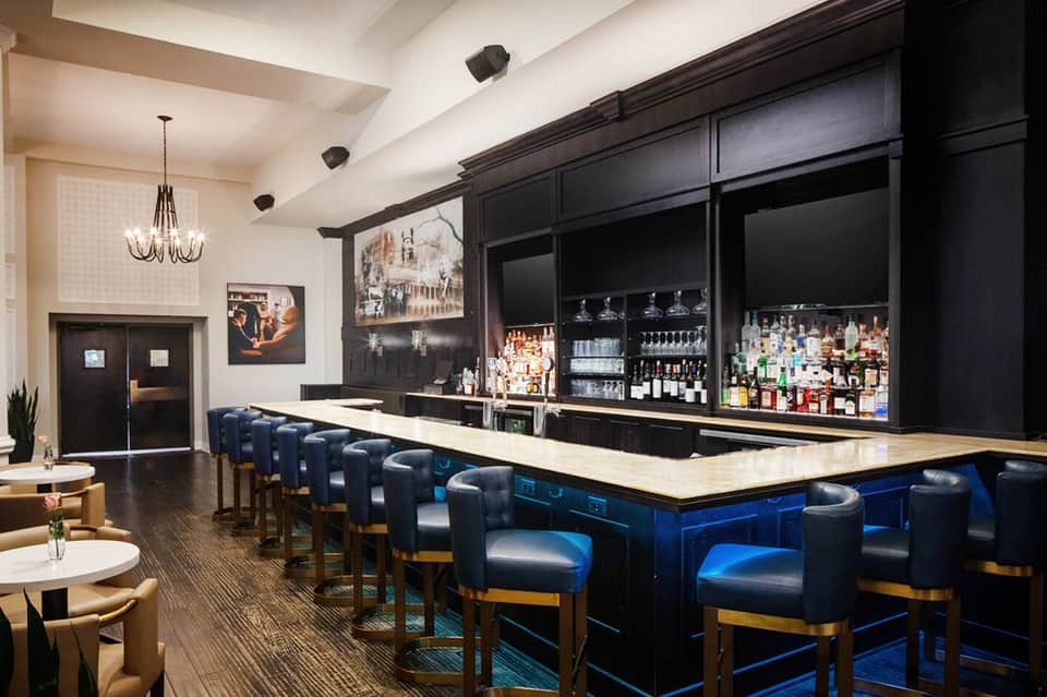 Elegant bar interior with navy leather barstools and extensive liquor collection