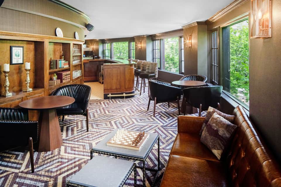 Sophisticated hotel lounge with wood finishes, leather seating, bar, and floor-to-ceiling windows