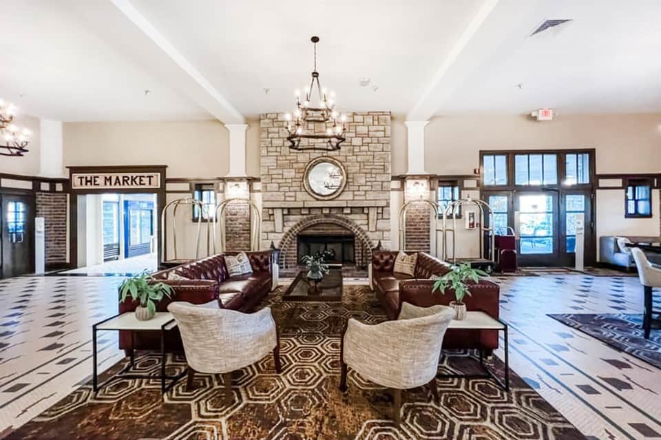 Elegant hotel lobby with fireplace, chandelier, leather seating, and decorative floor