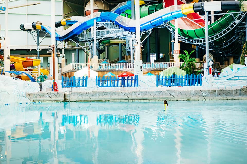 Indoor water park with blue water slides, wave pool, and colorful facilities with white railings