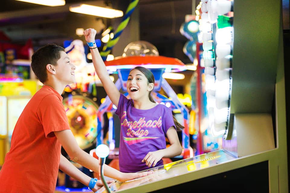 Children playing arcade games in colorful game room with bright lighting and entertainment machines