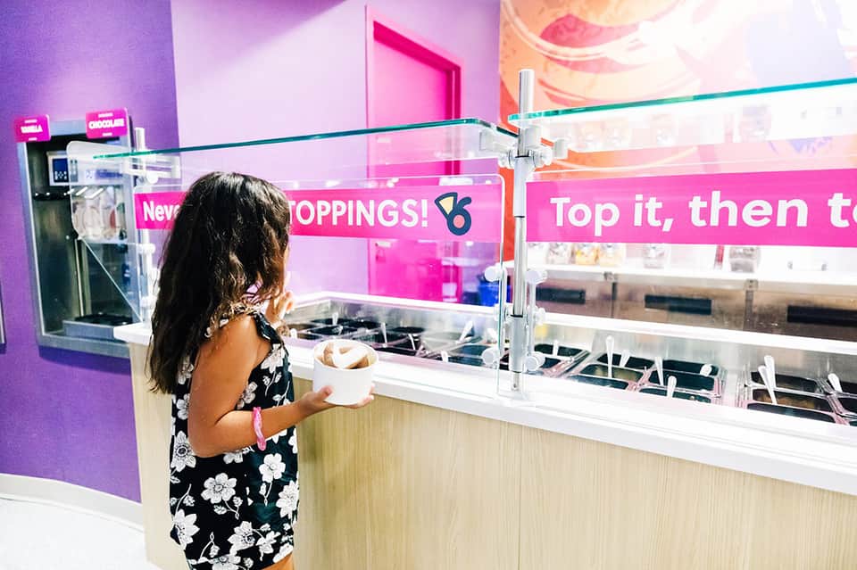 Customer ordering colorful ice cream or frozen treats at bright pink-themed counter