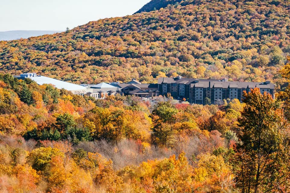 Mountain resort nestled in autumn foliage with orange and gold trees in scenic valley landscape