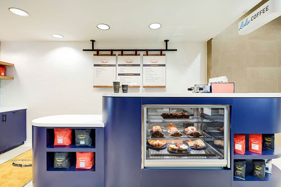 Modern coffee shop interior with navy counter, display case, and menu boards