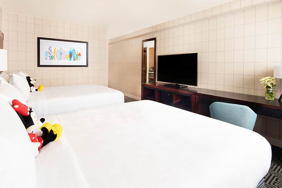 Hotel room with two queen beds, TV, and colorful decorative pillows