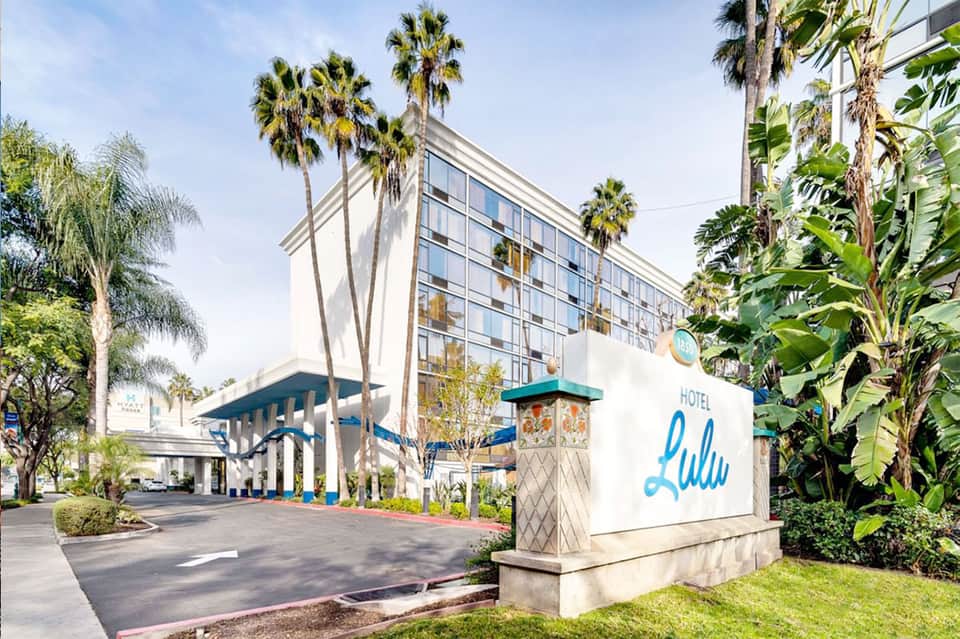 Hotel Lulu entrance with modern architecture, palm trees, and covered driveway