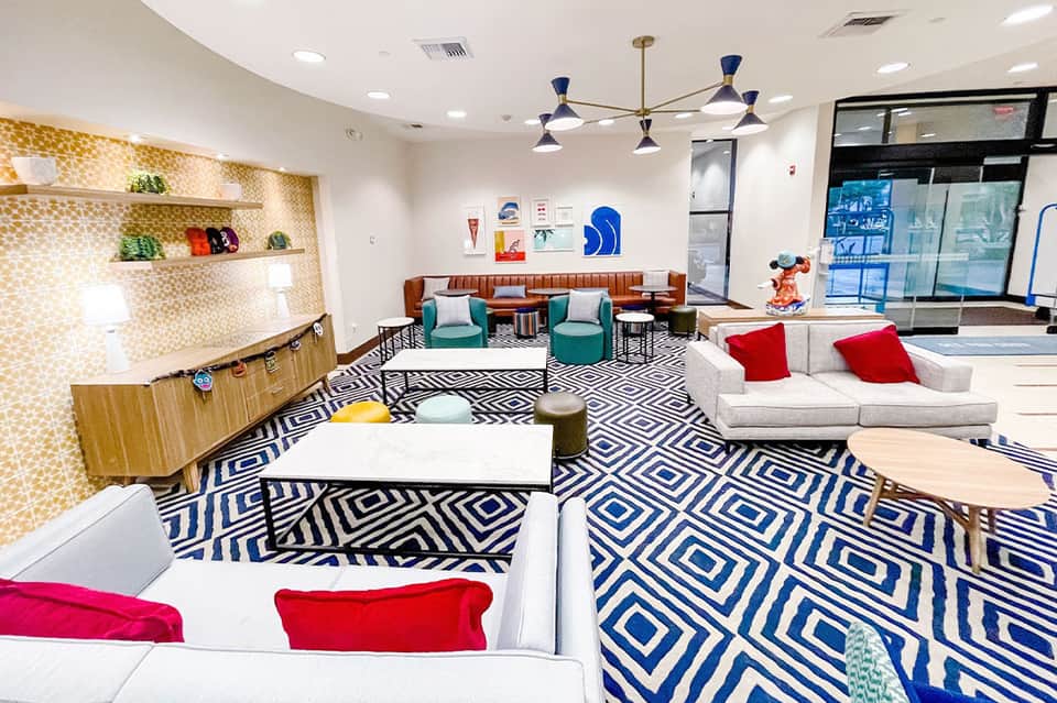 Modern lobby lounge with geometric patterned flooring, colorful seating, and mid-century light fixtures