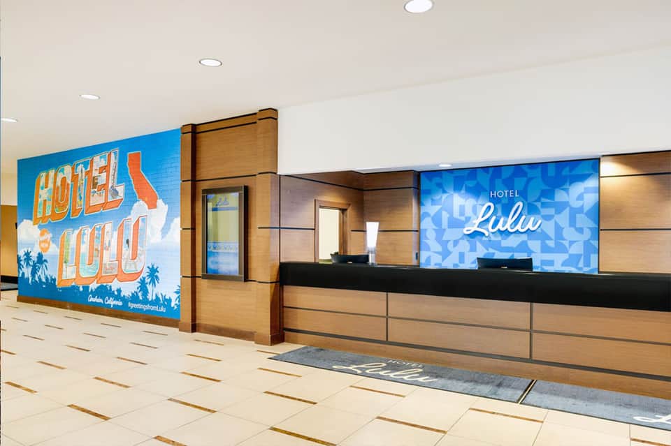 Hotel reception desk with retro sign and blue digital display in modern lobby setting