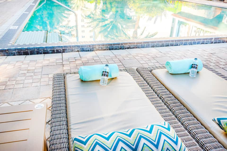 Poolside lounge chairs with towels and water bottles overlooking a resort pool