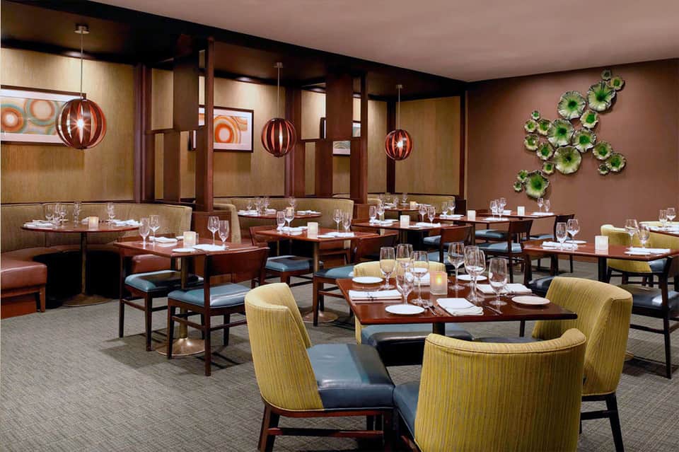 Elegant dining room with wood paneling, hanging lights, and booth seating