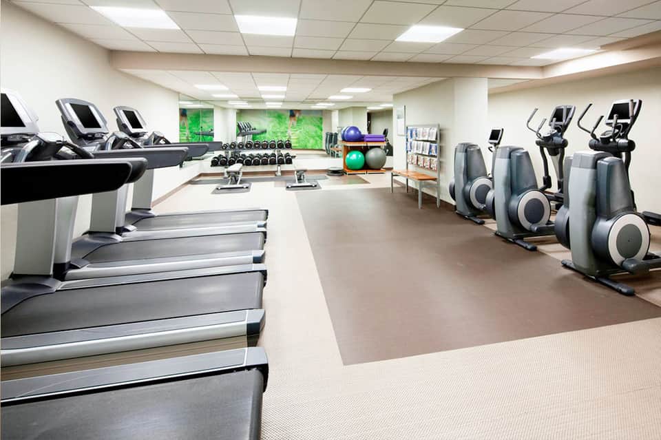 Modern fitness center with treadmills, exercise equipment, and dumbbells