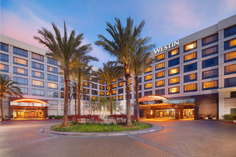 Modern Westin hotel entrance at dusk with palm trees, illuminated entrance, and courtyard