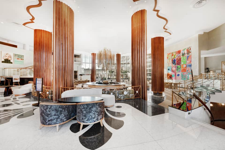 Luxury hotel lobby with tall copper sculptural columns, curved furniture, and artistic installations