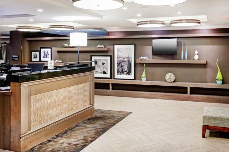 Hotel lobby featuring curved reception desk, wood accents, modern lighting, and contemporary artwork