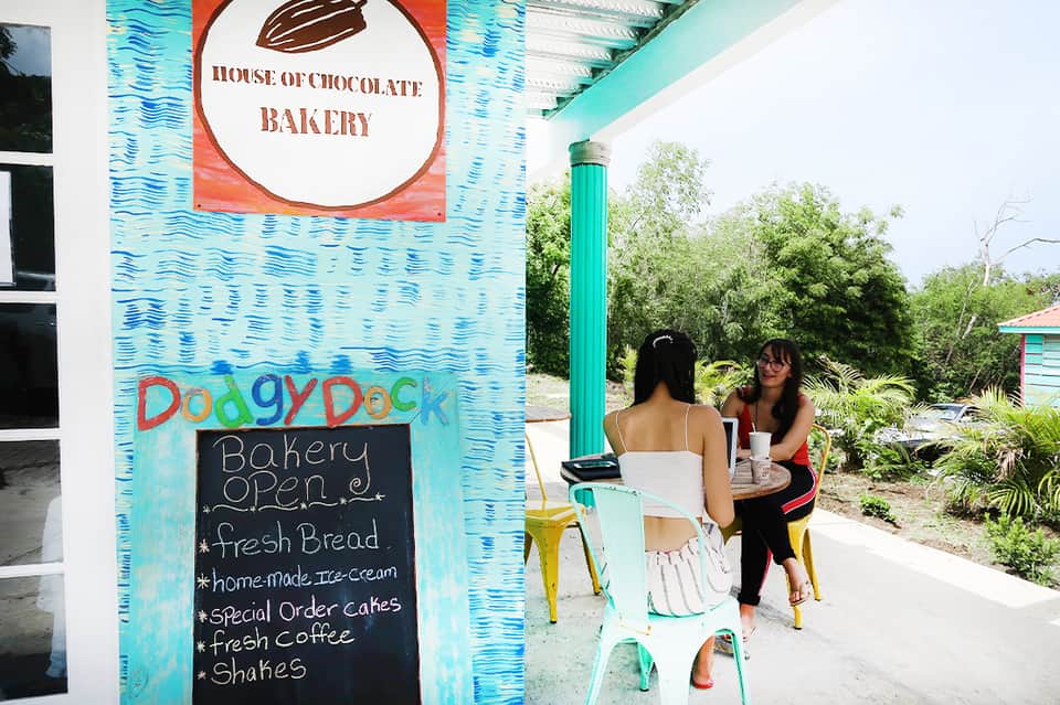 Colorful turquoise bakery storefront with two women at outdoor seating