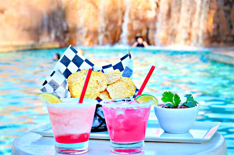 Tropical beachside cocktails with pink drinks, checkered flags, and tortilla chips overlooking turquoise water