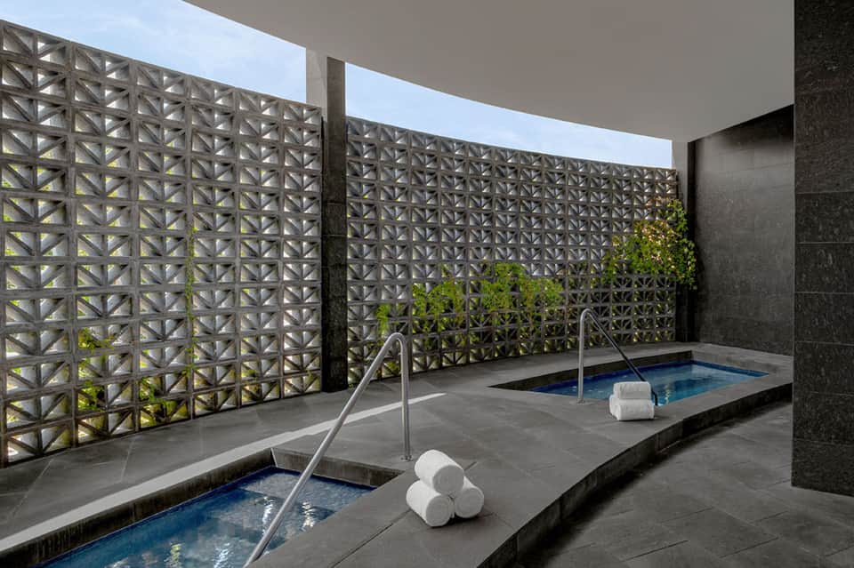 Modern spa area with two soaking pools and decorative lattice privacy screens