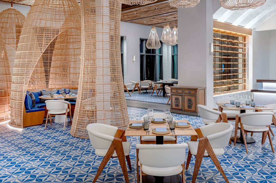Modern restaurant interior with woven pendant lights, blue patterned floor, and wooden furniture