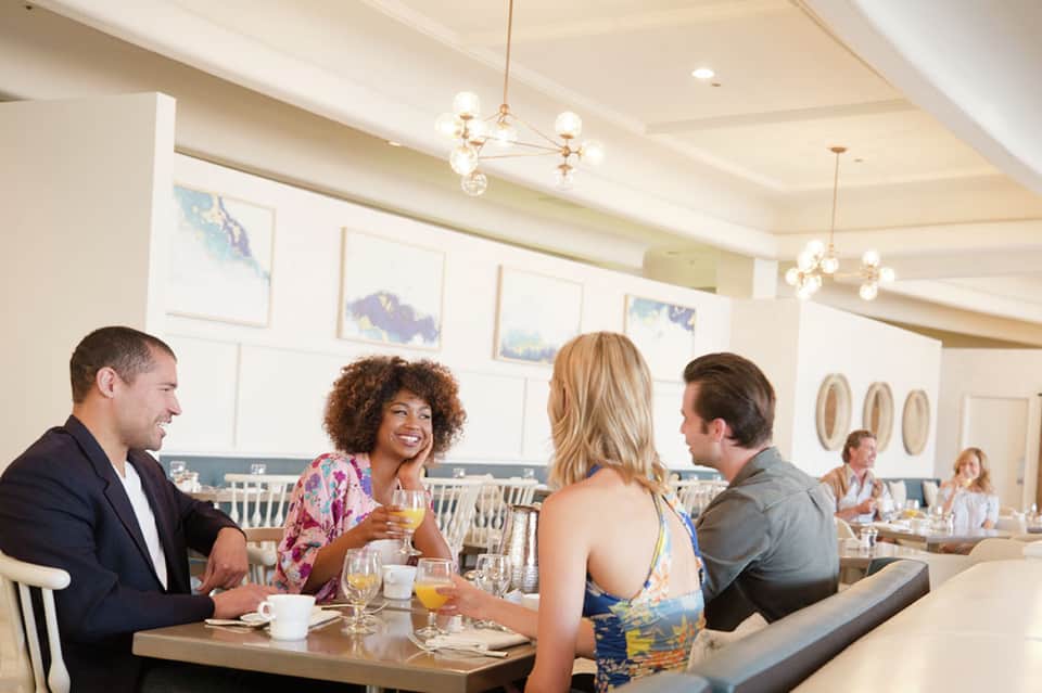 Upscale hotel dining room with guests enjoying breakfast and beverages