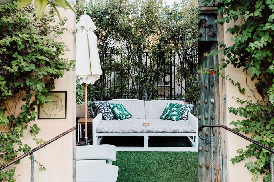Intimate courtyard seating area with white sofa and lush green ivy walls