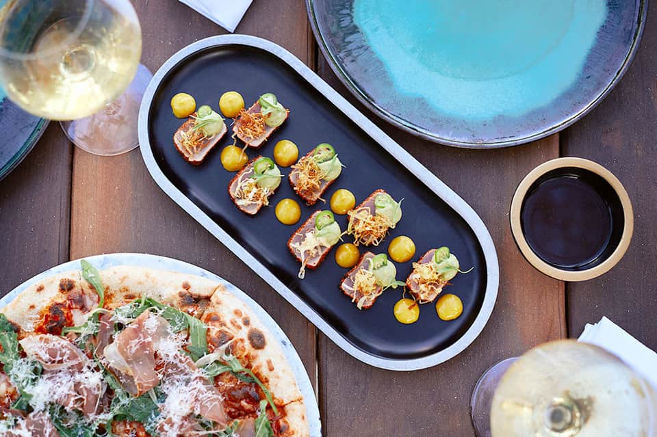 Overhead view of gourmet appetizers and wine at a poolside dining table