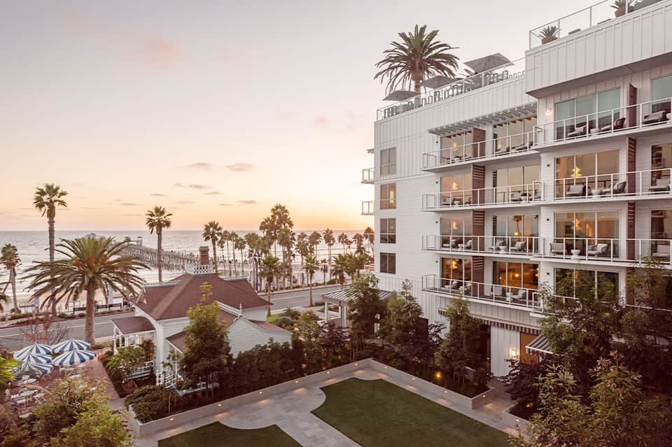 Beachfront resort at dusk with palm trees, multi-story white building, and coastal views