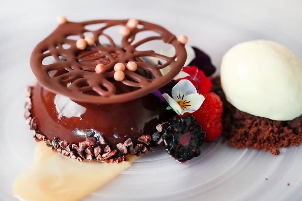 Plated chocolate dessert with decorative elements and fresh berries on white plate