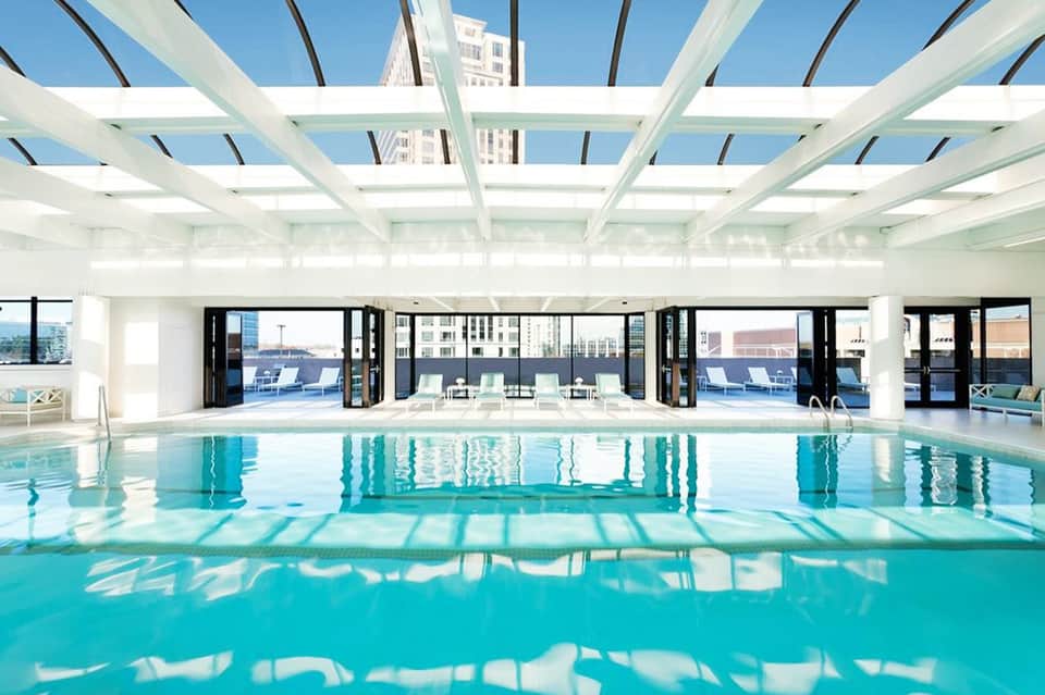 Indoor lap pool with glass ceiling, white structural beams, and modern architectural design