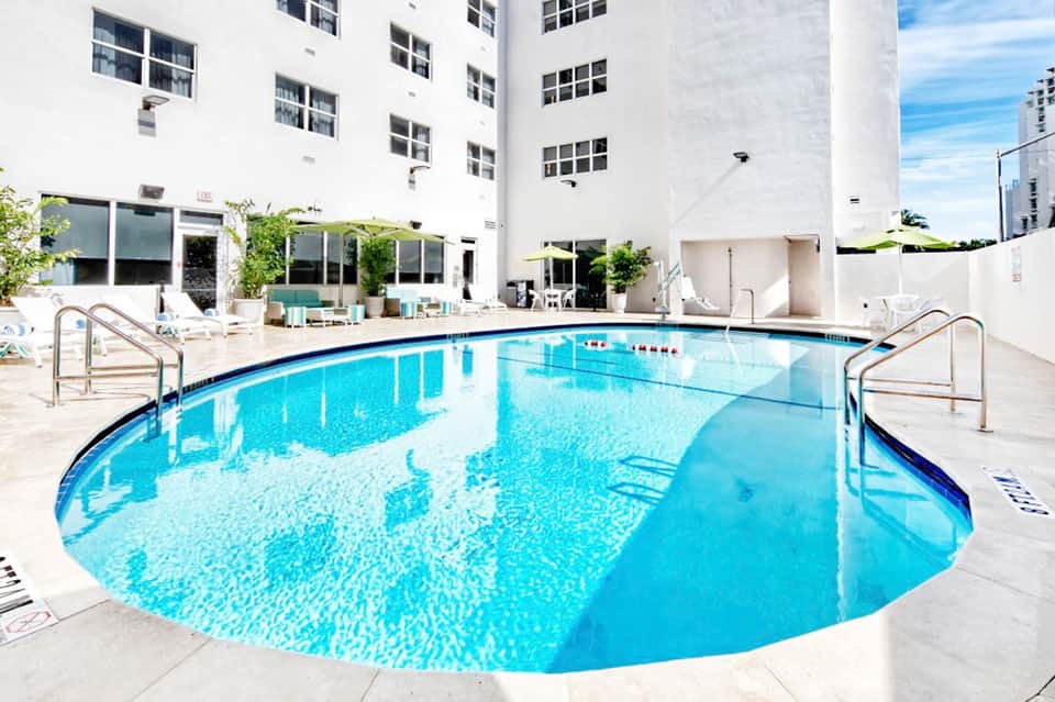 Resort indoor swimming pool surrounded by white walls and large windows in modern facility