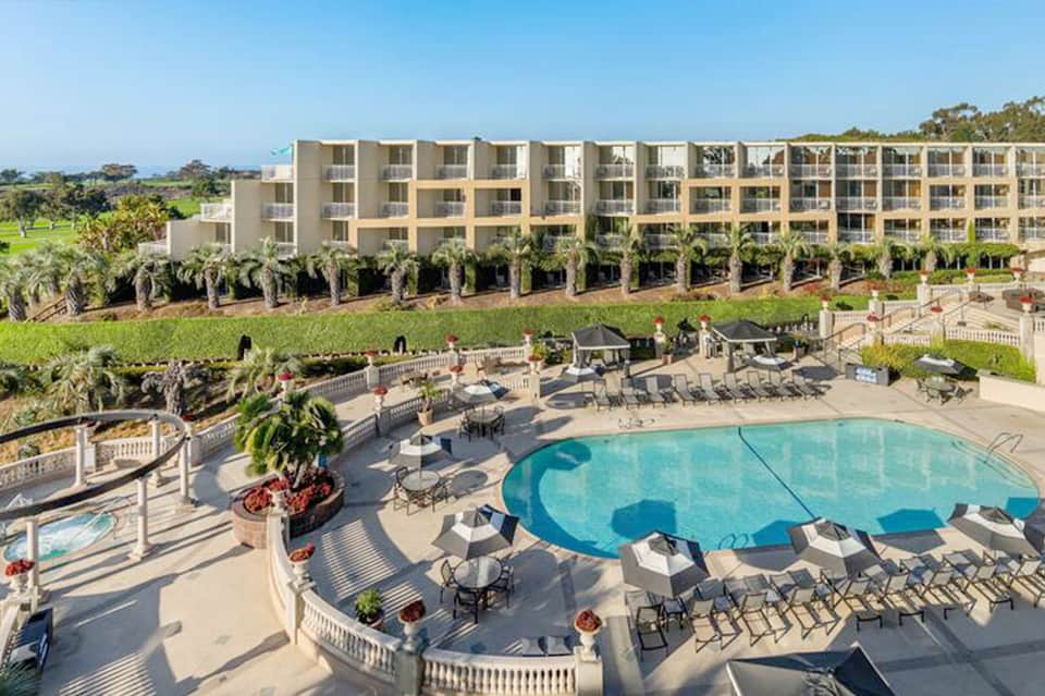 Beachfront resort with multi-story building, pool, and manicured grounds overlooking water