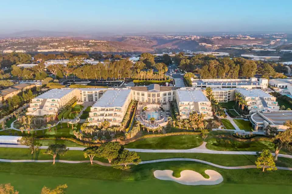 Aerial view of luxury resort with white buildings, golf course, gardens, and waterways